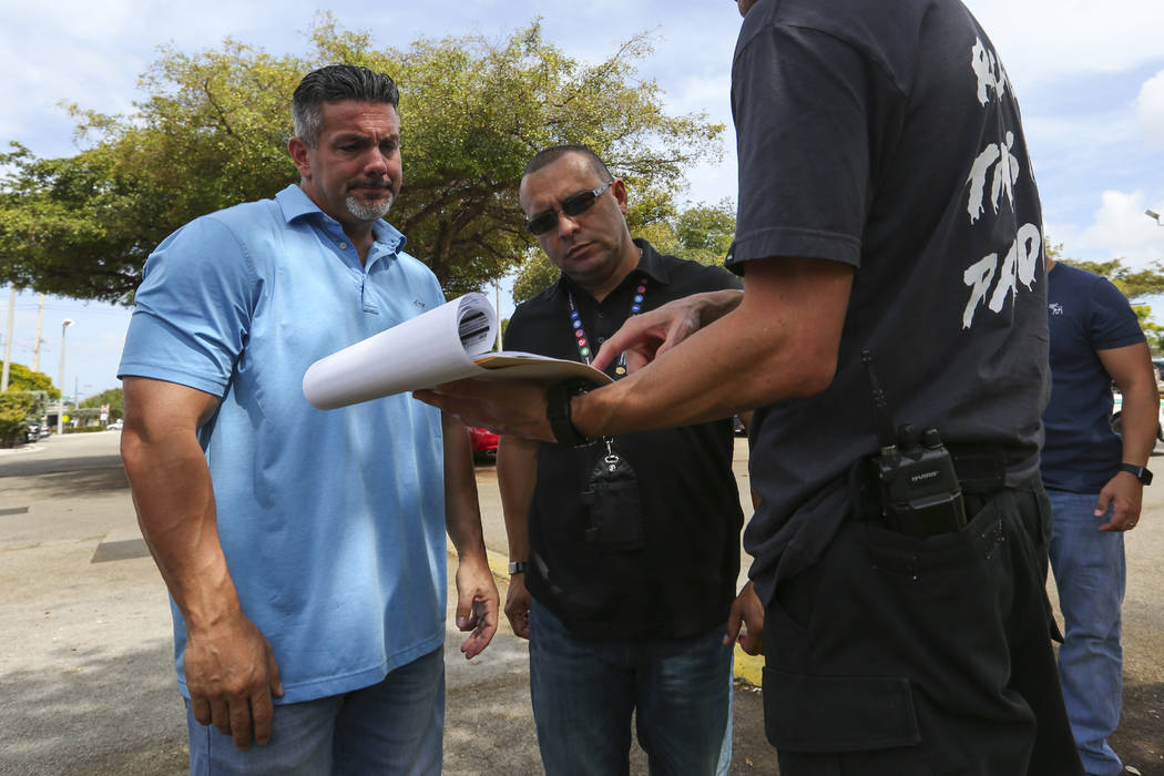 Miami-Dade Police Detective Daniel Garcia, right, briefs Lt. Carlos Gonzalez, far left, and public information officer Alvaro Zabaleta before conducting an operation to remove squatters from a hou ...