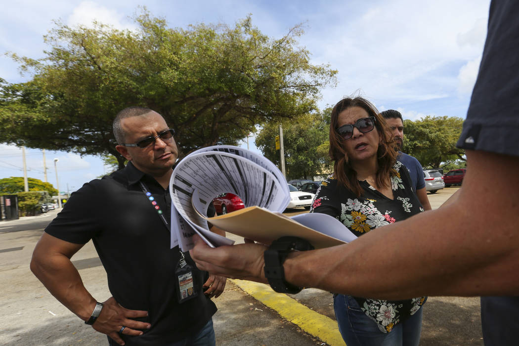 Miami-Dade Police Detective Daniel Garcia, far right, briefs public information officer Alvaro Zabaleta, left, and Detective Ivette Perez before conducting an operation to remove squatters from a  ...