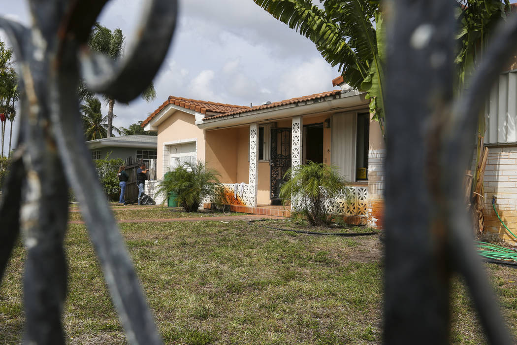 Miami-Dade police officers search a home during an operation to remove squatters from a house in Miami on Tuesday, April 18, 2017. Matias J. Ocner