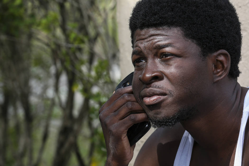 A suspected squatter makes a phone call after being removed from a house in Miami by Miami-Dade police officers on Tuesday, April 18, 2017. Matias J. Ocner