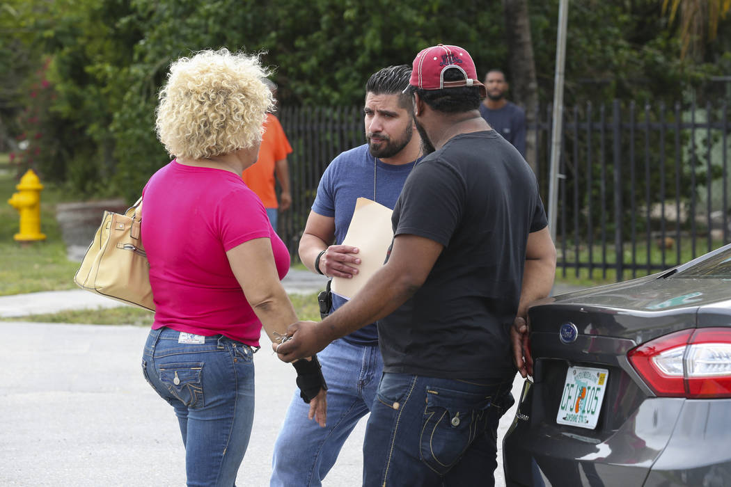 Miami Dade Police Sgt. Carlos Luffi, center, tells Valentina De Leon, left, and her husband that police cannot remove suspected squatters from their house in Miami on Tuesday, April 18, 2017. Mati ...