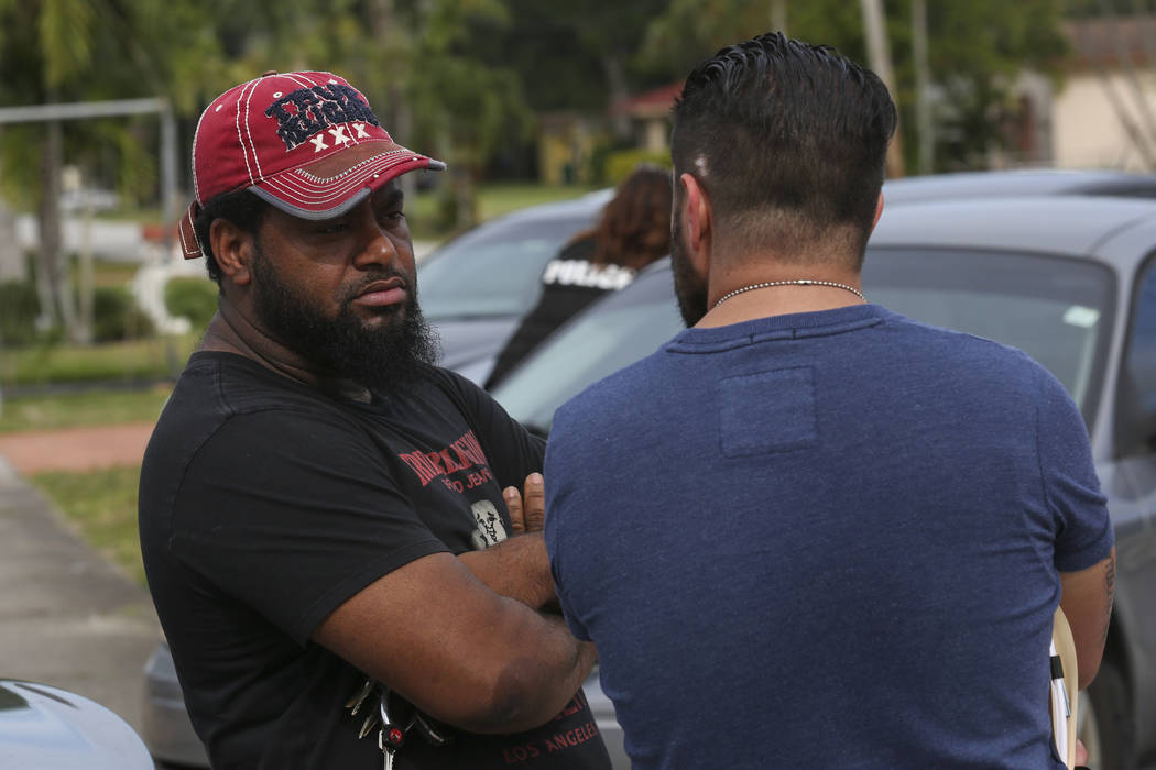 Miami Dade Police Sgt. Carlos Luffi, right, tells a homeowner that police cannot remove suspected squatters from his house in Miami on Tuesday, April 18, 2017. Matias J. Ocner