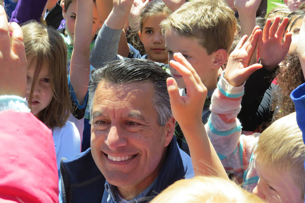 Gov. Brian Sandoval is surrounded by young faces after signing Assembly Bill 385 at a signing ceremony in Genoa on Friday, May 12, 2017. The "Kids in Parks" law gives every Nevada fifth-grader, an ...