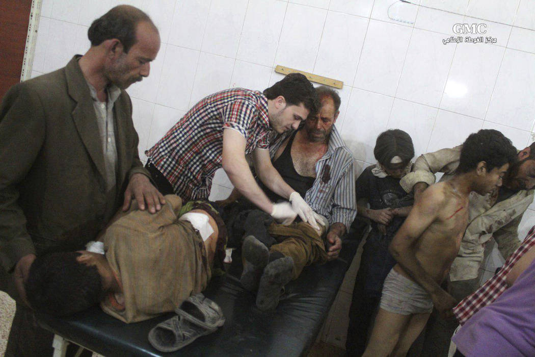 This photo provided by the Syrian anti-government activist group Ghouta Media Center, which has been authenticated based on its contents and other AP reporting, shows a Syrian doctor, center, trea ...