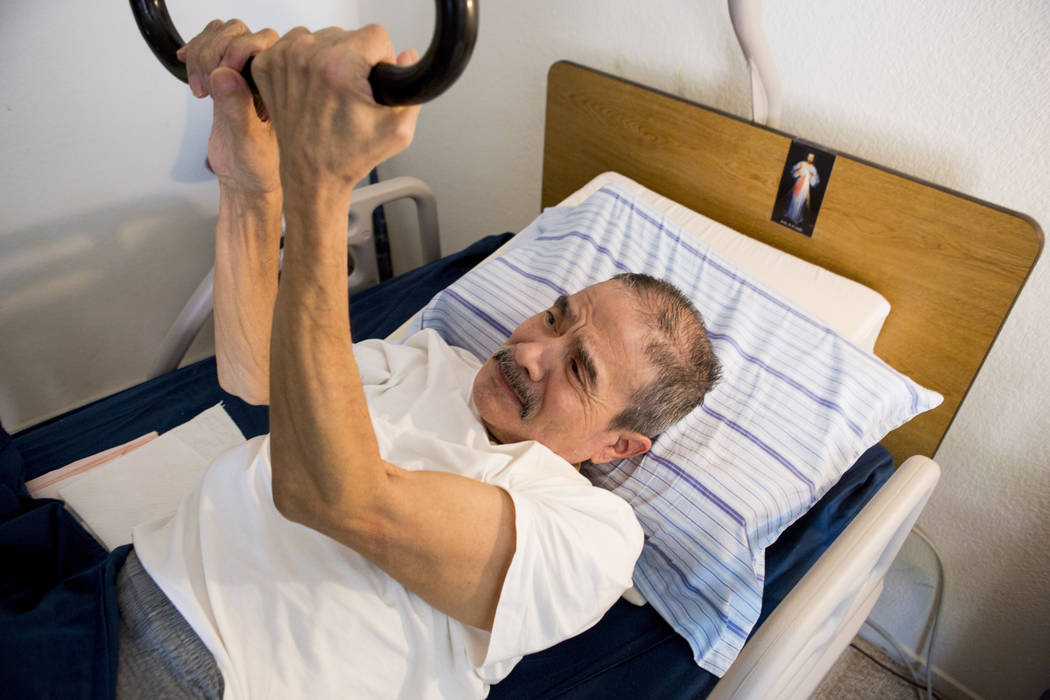 Rafael Santiago-Figueroa who suffers from multiple sclerosis readjusts in his bed while his wife puts away his Meals on Wheels delivery in their home in Las Vegas, Thursday, May 25, 2017. Elizabet ...