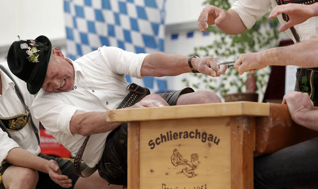 Georg Schoettl tries to pull his opponent over the table at the 40th Alpine Country Championships in Fingerhakeln_finger wrestling_ in Woernsmuehl, Germany, Thursday, May 25, 2017. Competitors bat ...