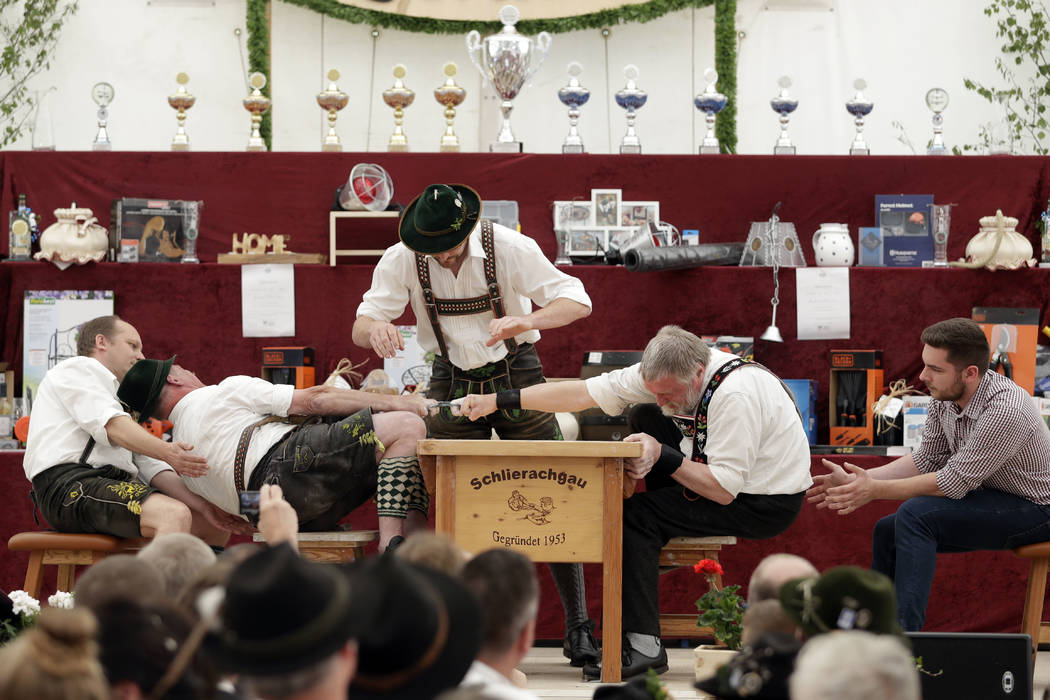 A man dressed in traditional clothes tries to pull his opponent over the table at the 40th Alpine Country Championships in Fingerhakeln in Woernsmuehl, Germany, Thursday, May 25, 2017. Competitors ...