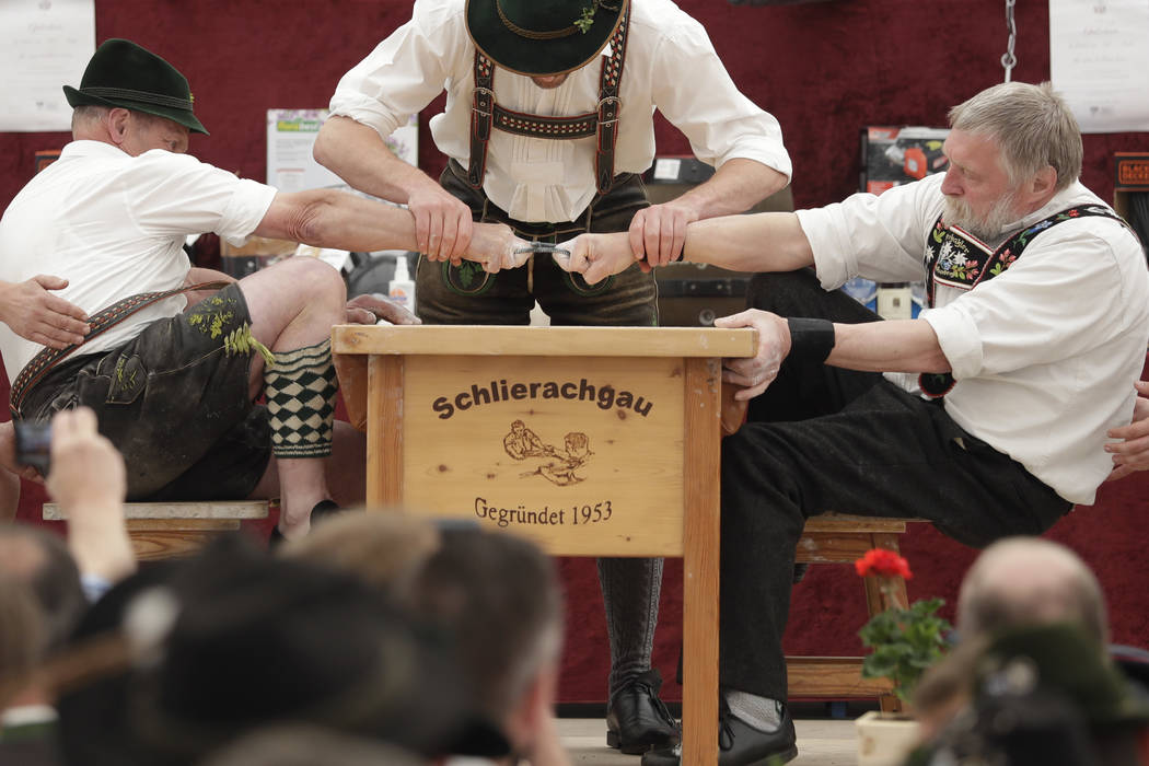 A man dressed in traditional clothes tries to pull his opponent over the table during the 40th Alpine Country Championships in Fingerhakeln_finger wrestling_ in Woernsmuehl, Germany, Thursday, May ...