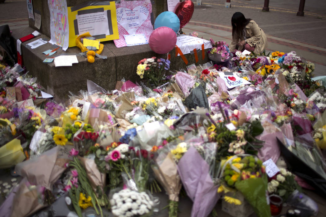 A woman places flowers at a memorial for the victims of a suicide attack at a concert by Ariana Grande that killed more than 20 people Monday night in central Manchester, Britain, Wednesday, May 2 ...