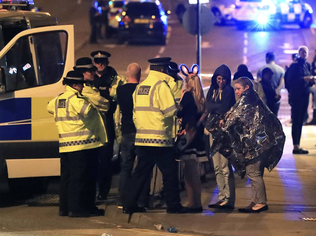 Emergency services personnel speak to people outside Manchester Arena after reports of an explosion at the venue during an Ariana Grande concert in Manchester, England, Monday, May 22, 2017. (Pete ...