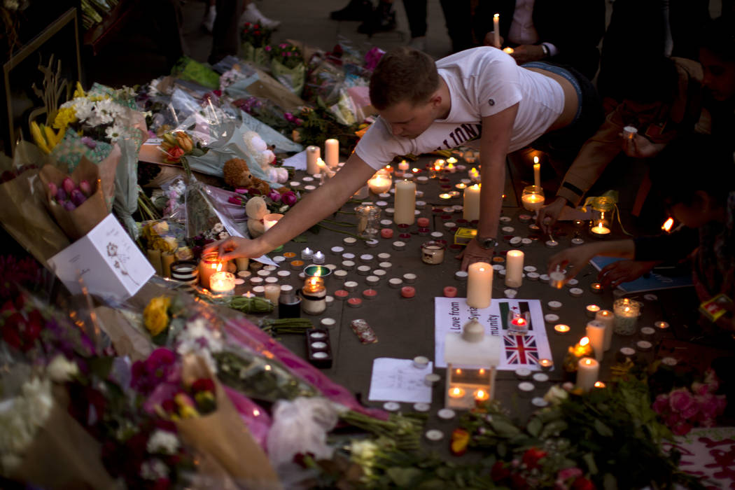 A man lights candles after a vigil in Albert Square, Manchester, England, Tuesday May 23, 2017, the day after the suicide attack at an Ariana Grande concert that left 22 people dead as it ended on ...