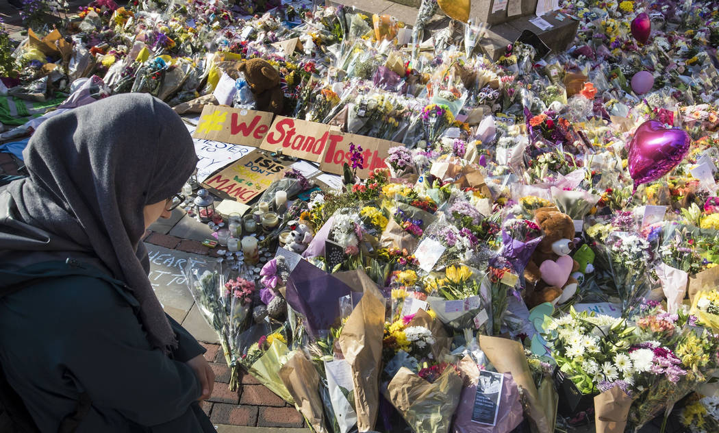 A woman looks at the floral tributes and messages left for the victims of the concert blast, during a vigil at St Ann's Square in central Manchester, England, Wednesday, May 24, 2017. ﻿&#xf ...