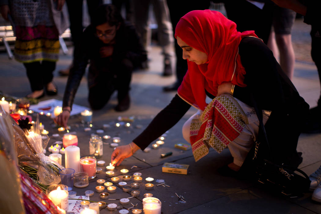 A woman lights candles after a vigil in Albert Square, Manchester, England, Tuesday May 23, 2017, the day after the suicide attack at an Ariana Grande concert that left 22 people dead as it ended ...