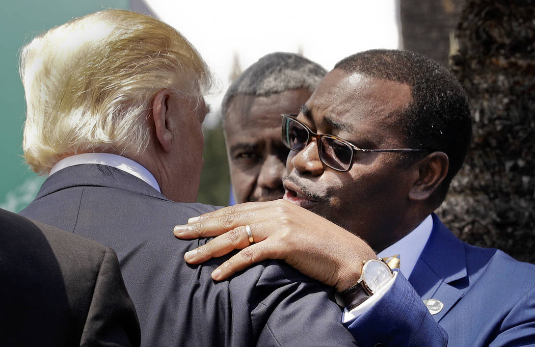 Akinwumi Adesina, President of the African Development Bank, hugs U.S. President Donald Trump after a family photo of G7 leaders and Outreach partners, in the Sicilian town of Taormina, Italy, Sat ...