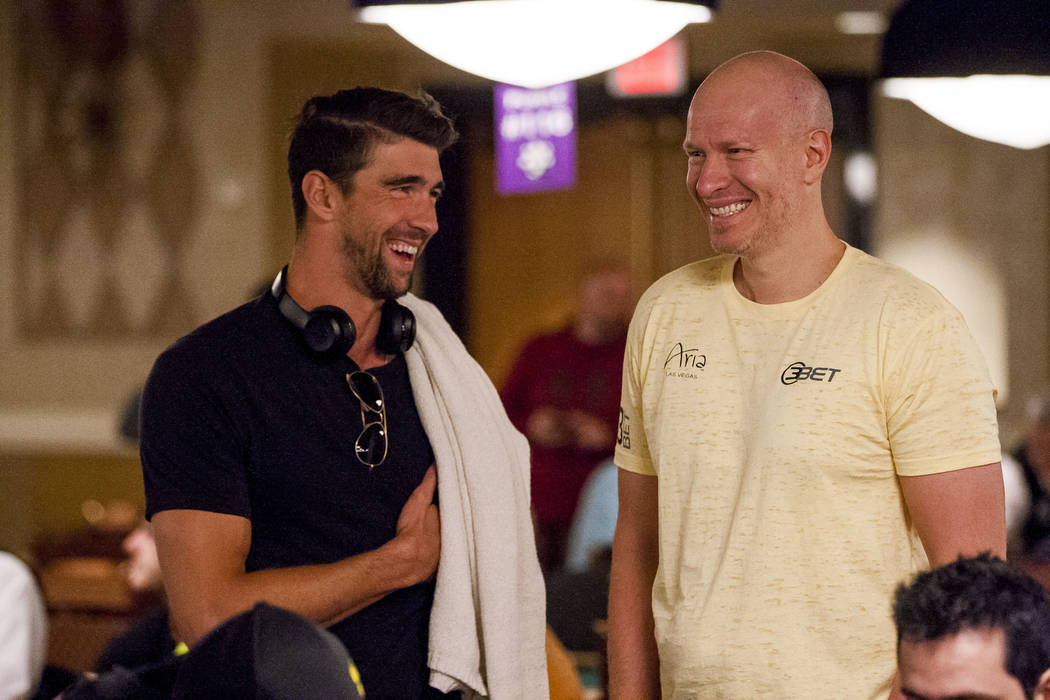 Olympic swimmer Michael Phelps talks with Greg Mueller, a professional poker player and former professional hockey player, before a tag team event in the opening of the World Series of Poker at th ...
