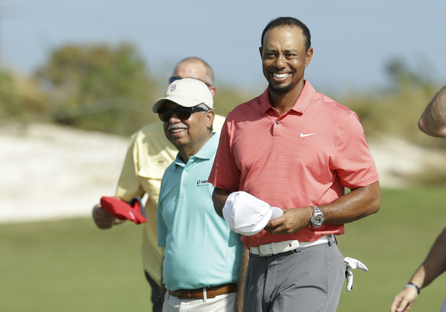 Tiger Woods, right, walks off the 18th green with Pawan Munjal, CEO of Hero MotoCorp, left, during the Pro-Am at the Hero World Challenge golf tournament, Wednesday, Nov. 30, 2016, in Nassau, Baha ...