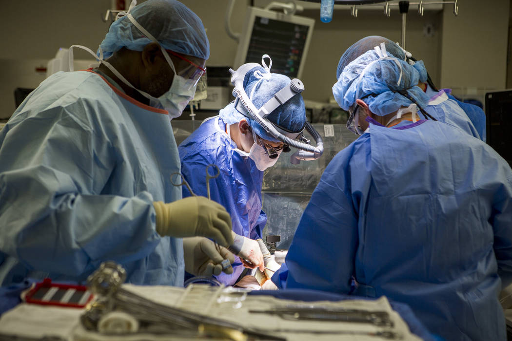 Dr. Quynh Feikes performs a surgery to fix an abdominal aneurysm with assistance from John Cousett, a certified heart scrub tech, left, Dr. Deepak Malhotra, back right, and assistant Tracy Blanken ...
