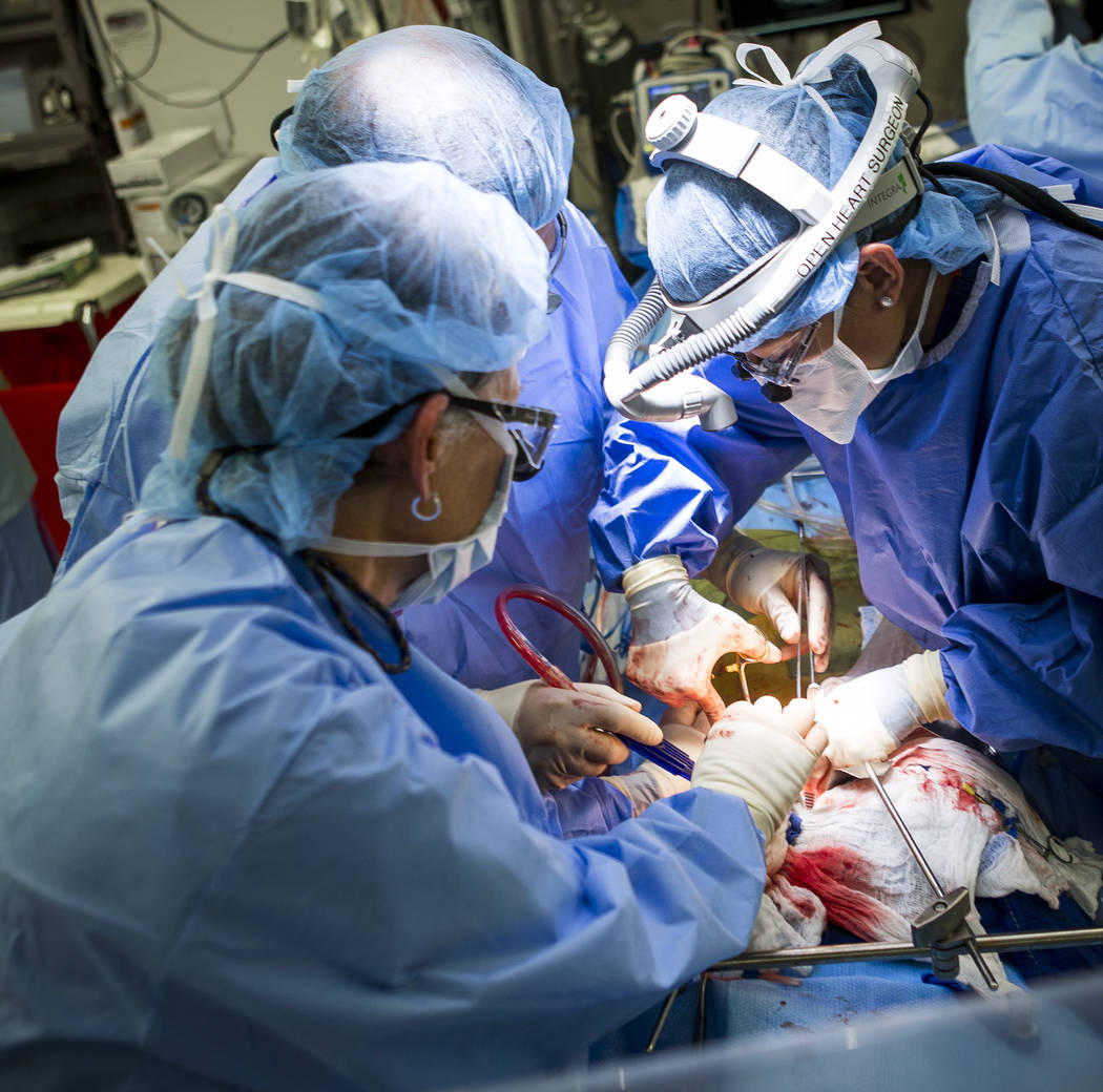 Dr. Quynh Feikes, right, performs a surgery to fix an abdominal aneurysm with help from assistant Tracy Blankenship, left, and Dr. Deepak Malhotra at University Medical Center on Tuesday, May 23,  ...