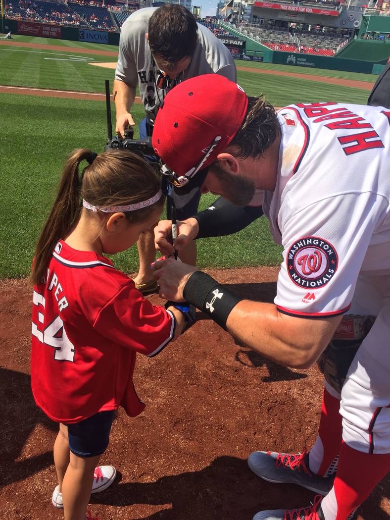Las Vegas' Bryce Harper signs the baseball for fellow Las Vegan Hailey Dawson after she threw out the ceremonial first pitch before the June 11 game between the Washington Nationals and Texas Rang ...
