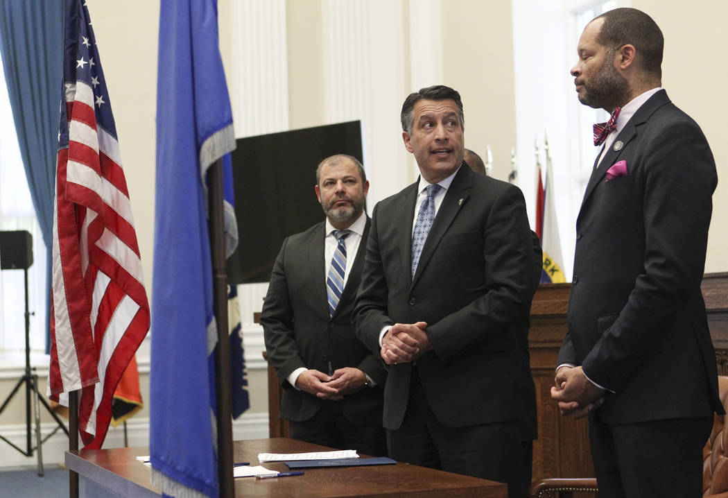 Gov. Brian Sandoval, center, speaks before signing a group of bills while flanked by Assembly Minority Floor Leader Paul Anderson, R-Las Vegas, left, and Senate Majority Leader Aaron Ford, D-Las V ...
