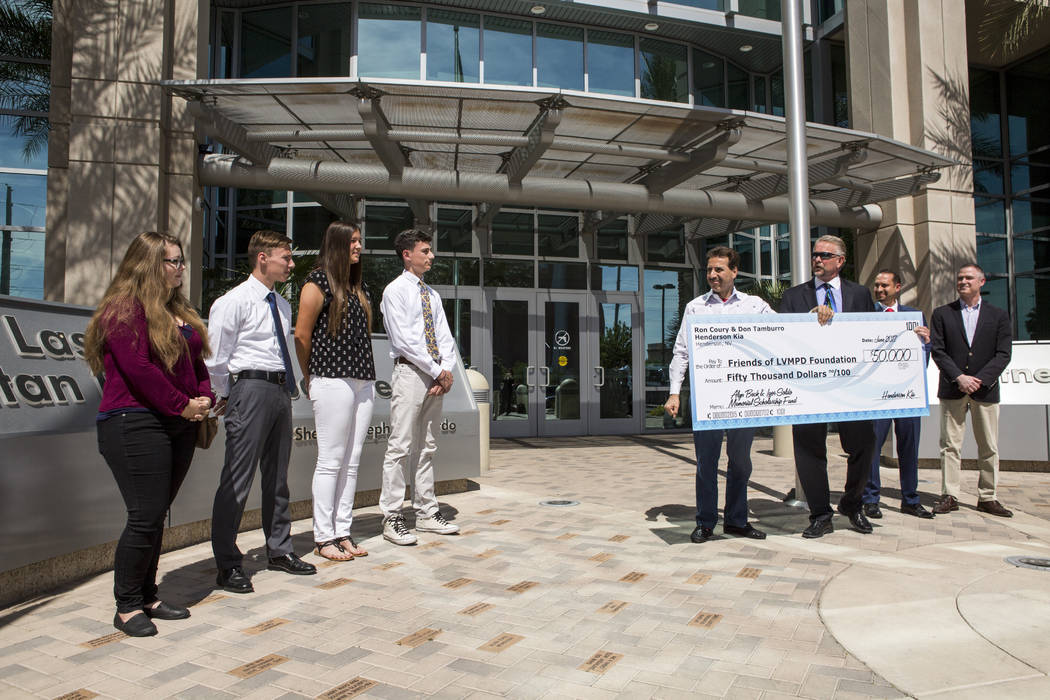 Ron Coury, co-owner of Henderson Kia and Friends of LVMPD Foundation Board member, presents a check for $50,000 to award ten high school graduates and college students scholarships of $5,000 each  ...