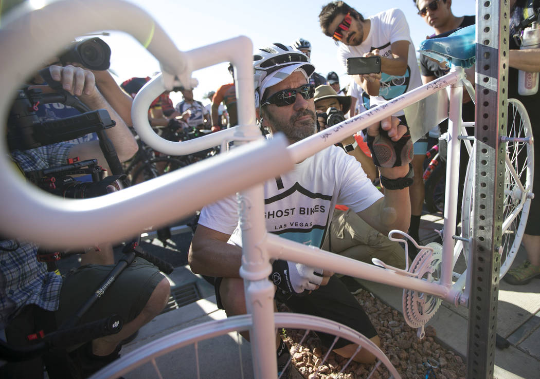 Pat Treichel, founder Ghost Bikes Las Vegas, writes a message on the ghost bike of Dr. Kayvan Khiabani during a memorial service at the corner South Pavillion Center Drive near West Charleston Bou ...