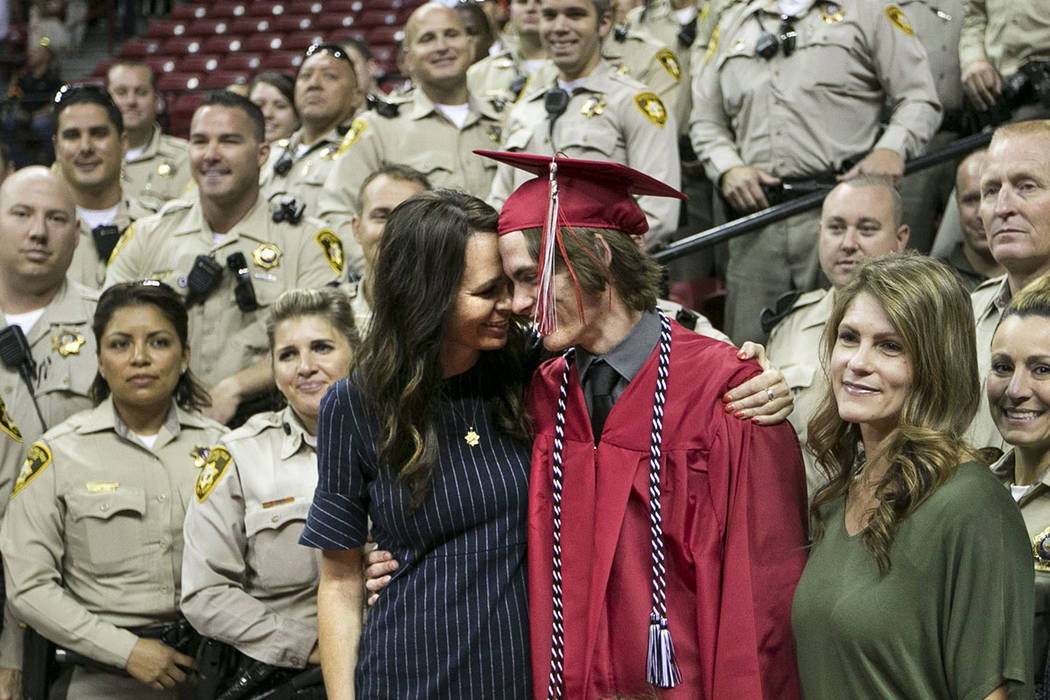 Daxton Beck gets a hug from his mother Nicole Beck as they gather for a photo with a group of Metro Officers following his graduation ceremony at Thomas and Mack in Las Vegas on Saturday, June 10, ...