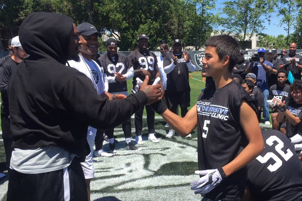 Raiders running back Marshawn Lynch (left) congratulates a teen who was presented the Best Sportsmanship Award at a football camp the Raiders hosted at their facility in Alameda, Calif., on June 1 ...