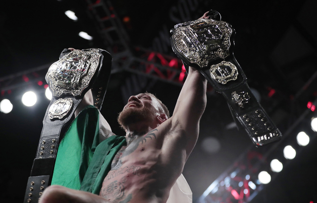 Conor McGregor holds up his title belts after he defeated Eddie Alvarez during a lightweight title mixed martial arts bout at UFC 205, early Sunday, Nov. 13, 2016, at Madison Square Garden in New  ...