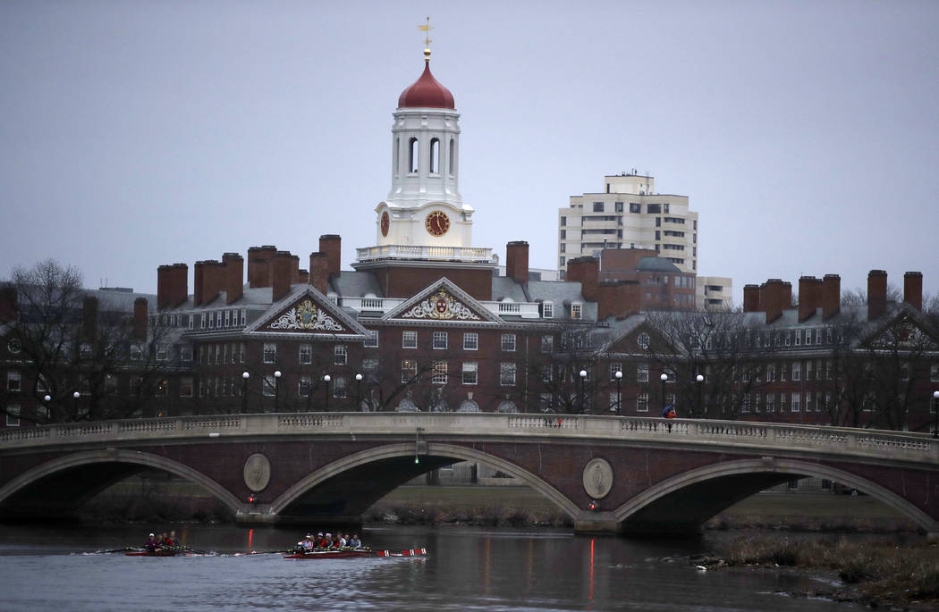 FILE - In this March 7, 2017 file photo, rowers paddle down the Charles River near the campus of Harvard University in Cambridge, Mass. A debate over the appropriateness of the school's decision t ...