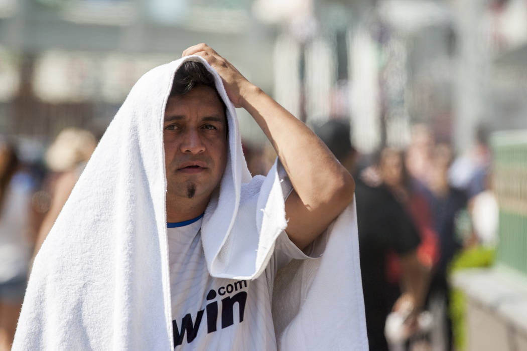 Luis M., a Las Vegas resident who declined to give his full last name, tries to stay shaded while coming back from a pool party on the Las Vegas Strip as the temperature reached 116 on Tuesday, Ju ...