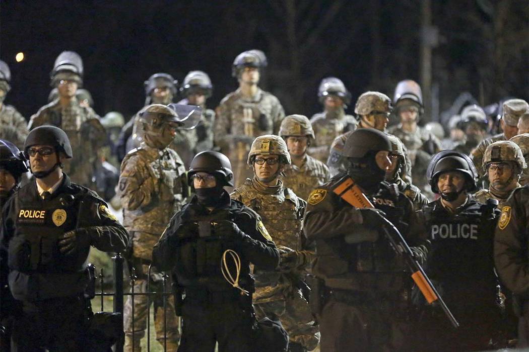 In this Friday, Nov. 28, 2014, file photo, police and Missouri National Guard stand guard as protesters gather in front of the Ferguson Police Department. The family of Michael Brown, who was kill ...