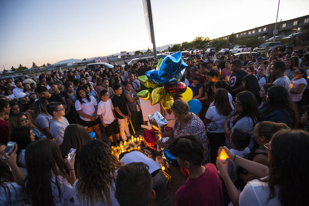 People gather during a candlelight vigil for teenagers Oscar Ayala and Moises Rivera, who both died in a crash caused by a drunk driver this past Saturday, at Marion Drive and Judah Avenue in Las  ...