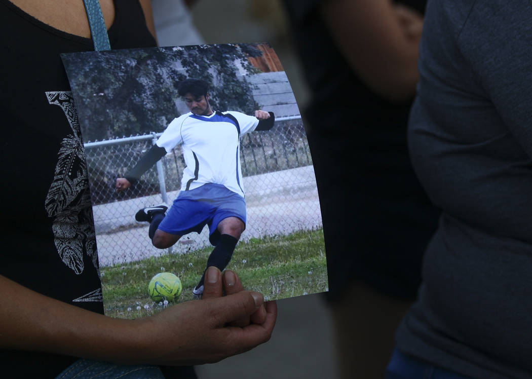 A woman holds a photo of Moises Rivera, 16, one of two teenagers who died in a crash caused by a drunk driver this past Saturday, during a candlelight vigil at Marion Drive and Judah Avenue in Las ...