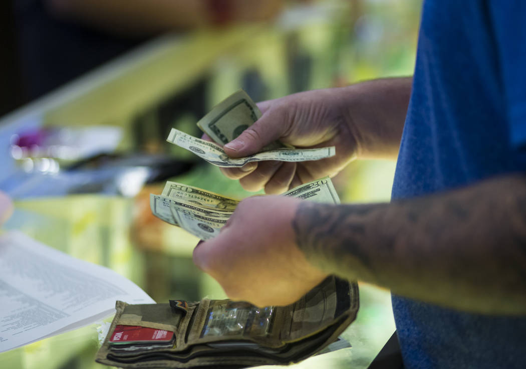 Henderson resident Ethan takes out cash to pay for marijuana products during the first day of recreational sales at Acres Cannabis in Las Vegas on Saturday, July 1, 2017. Chase Stevens Las Vegas R ...