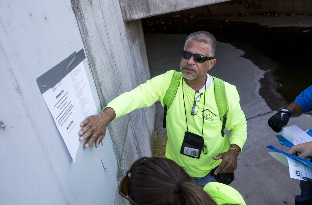 HELP of Southern Nevada employee Louis Lacey, the Mobile Crisis Intervention Team manager, puts up a sign warning the homeless about upcoming rain in monsoon season near flood tunnels under the Ha ...