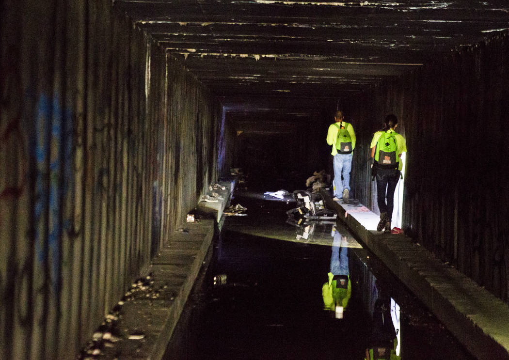 HELP of Southern Nevada employees Louis Lacey, front, and Hayli Petcoff lead the way and avoid sitting water along the side of a flood tunnel near the Hard Rock hotel-casino on Tuesday, June 27, 2 ...