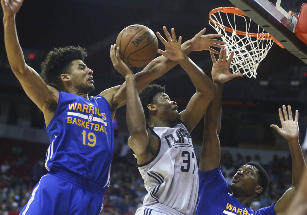 Golden State Warriors' Tai Webster (19) and Damian Jones, lower right, defend as Los Angeles Clippers' Isaiah Hicks (37) goes to the basket during a basketball game at the NBA Summer League at the ...