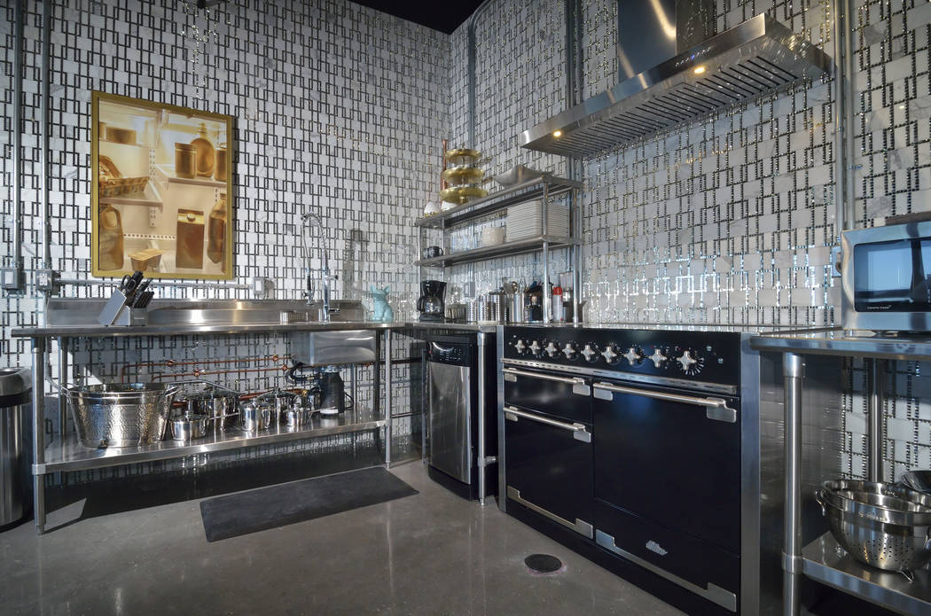 The kitchen is all about industrial style, but with a bit of glitz. It has no cabinets, utilizing open, commercial pieces instead. (Bill Hughes Real Estate Millions)