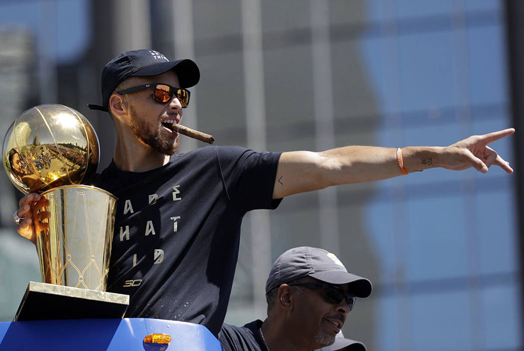 Golden State Warriors' Stephen Curry gestures while holding the Larry O'Brien  trophy during a parade and rally after winning the NBA basketball  championship, in Oakland, Calif. (AP Photo/Marcio Jo …