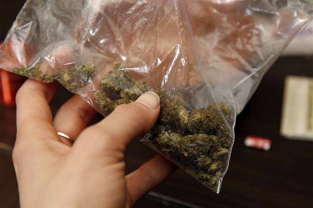 Rica Madrid poses for a photograph as she holds a bag of pot as she prepares to roll a joint in her home on the first day of legal possession of marijuana for recreational purposes, Thursday, Feb. ...
