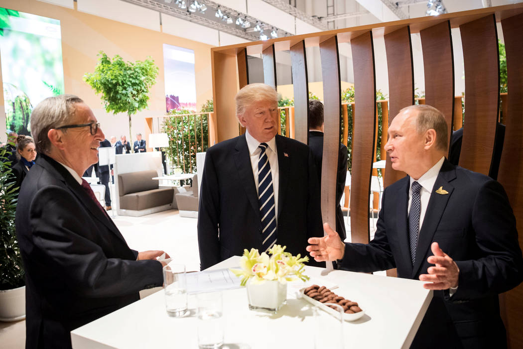U.S. President Donald Trump, Russia's President Vladimir Putin and President of the European Commission Jean-Claude Juncker talk during the G20 Summit in Hamburg, Germany in this still image taken ...