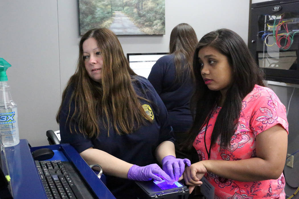 Gina Cavallero, left, fingerprint technician for the Clark County School District, rolls the finger of Paulcherry Gohetia, who is one of 82 teachers that the Clark County School District brought i ...