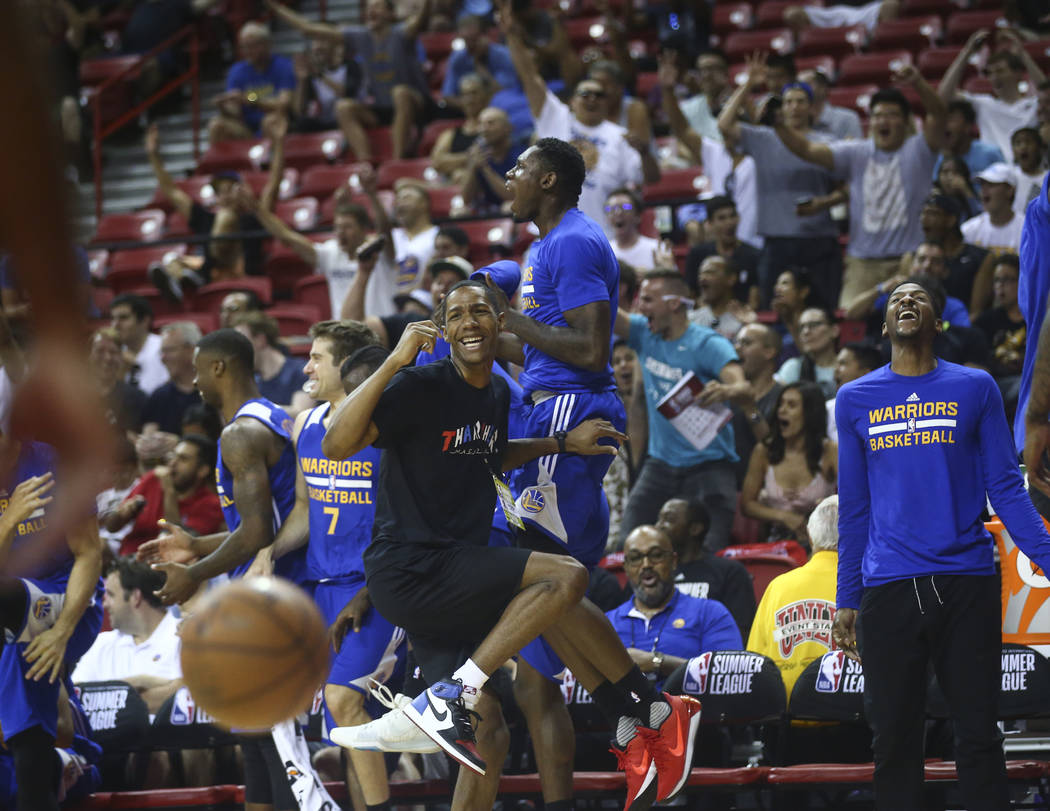 Golden State Warriors' Patrick McCaw, wearing black, reacts with the bench after a three-pointer from Golden State Warriors' Dylan Ennis during a basketball game against the Los Angeles Clippers a ...