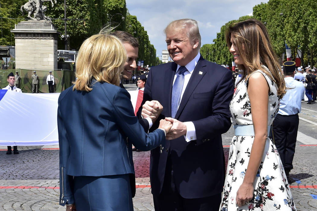 French President Emmanuel Macron second left shakes hands with U.S President Donald Trump while First Lady Melania Trump and Brigitte Macron left walk on sides after the Bastille Day military