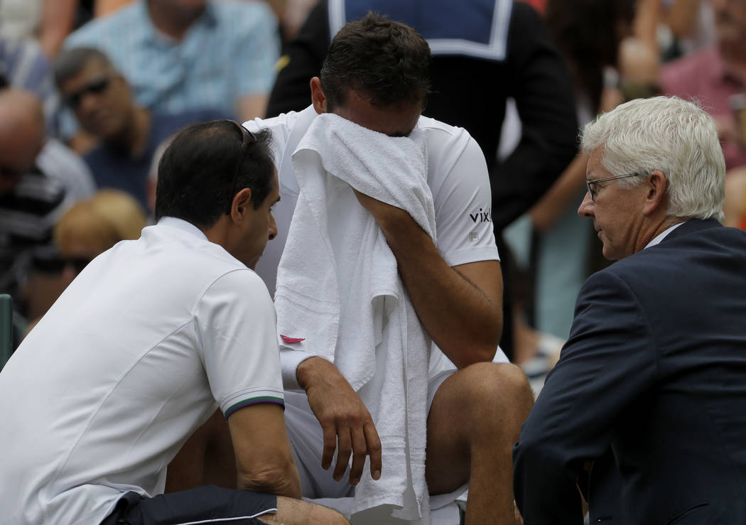 Croatia's Marin Cilic receives treatment during a change of ends break as he plays Switzerland's Roger Federer in the Men's Singles final match on day thirteen at the Wimbledon Tennis Championship ...