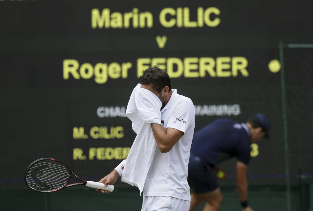 Croatia's Marin Cilic walks back to his seat after his service was broken by Switzerland's Roger Federer in the Men's Singles final match on day thirteen at the Wimbledon Tennis Championships in L ...