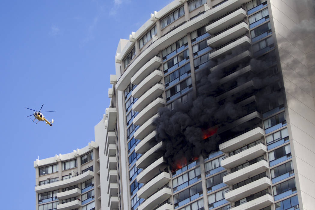 A Honolulu Fire Department helicopter flies near a fire burning on a floor at the Marco Polo apartment complex, Friday, July 14, 2017, in Honolulu. (Marco Garcia/AP)
