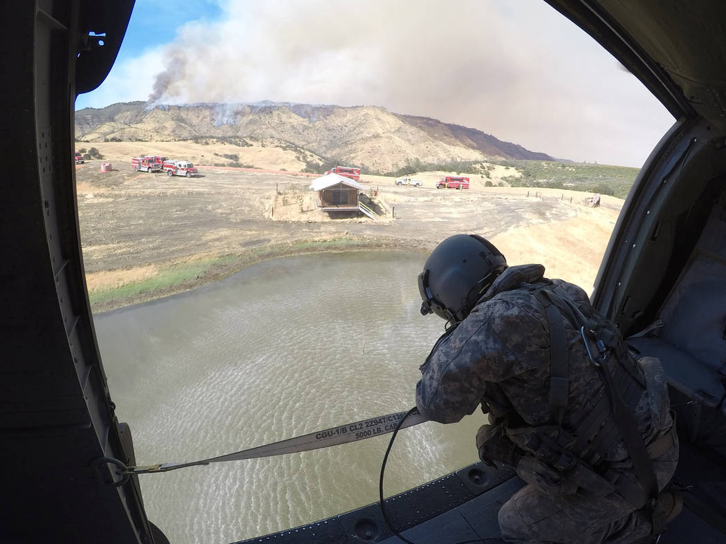 Staff Sergeant Ge Xiong, crew chief aboard a California Army National Guard UH-60 Black Hawk helicopter, watches a 2,600-gallon Bambi Bucket submerge into a pond July 13,2017, during the Garza fir ...