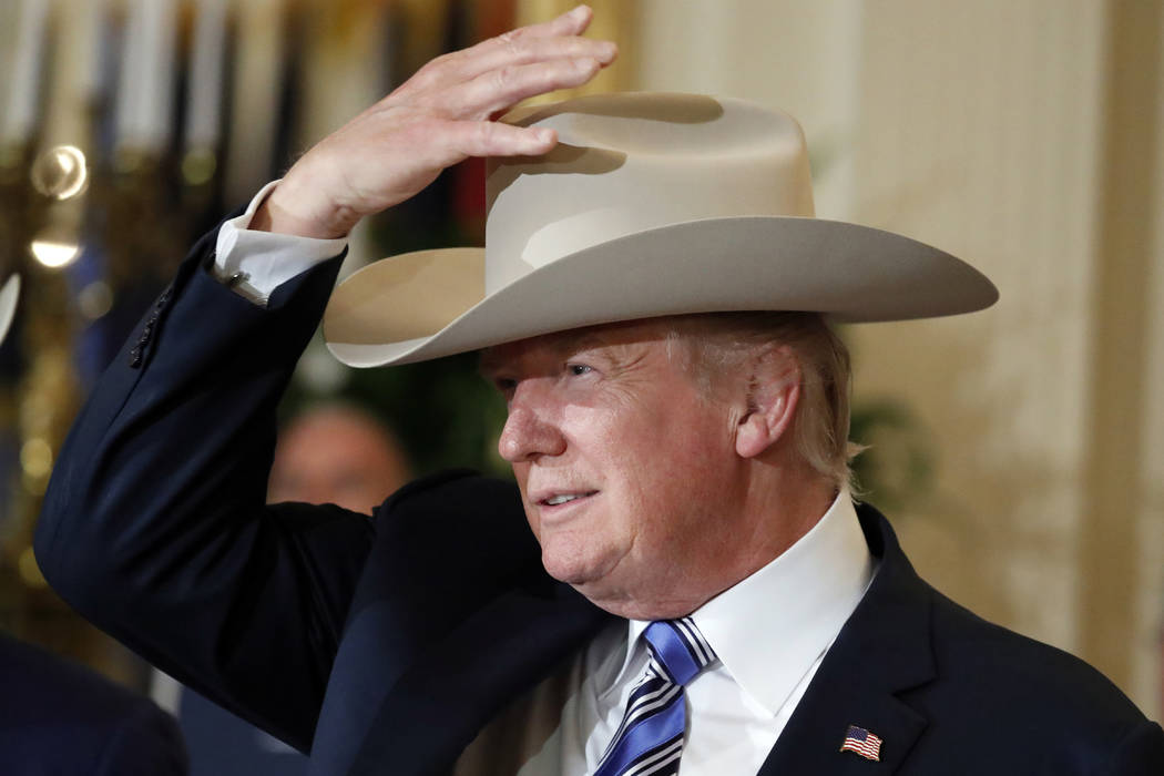 President Donald Trump tries on a Stetson hat during a "Made in America" product showcase featuring items created in each of the U.S. 50 states, Monday, July 17, 2017, at the White House in Washin ...